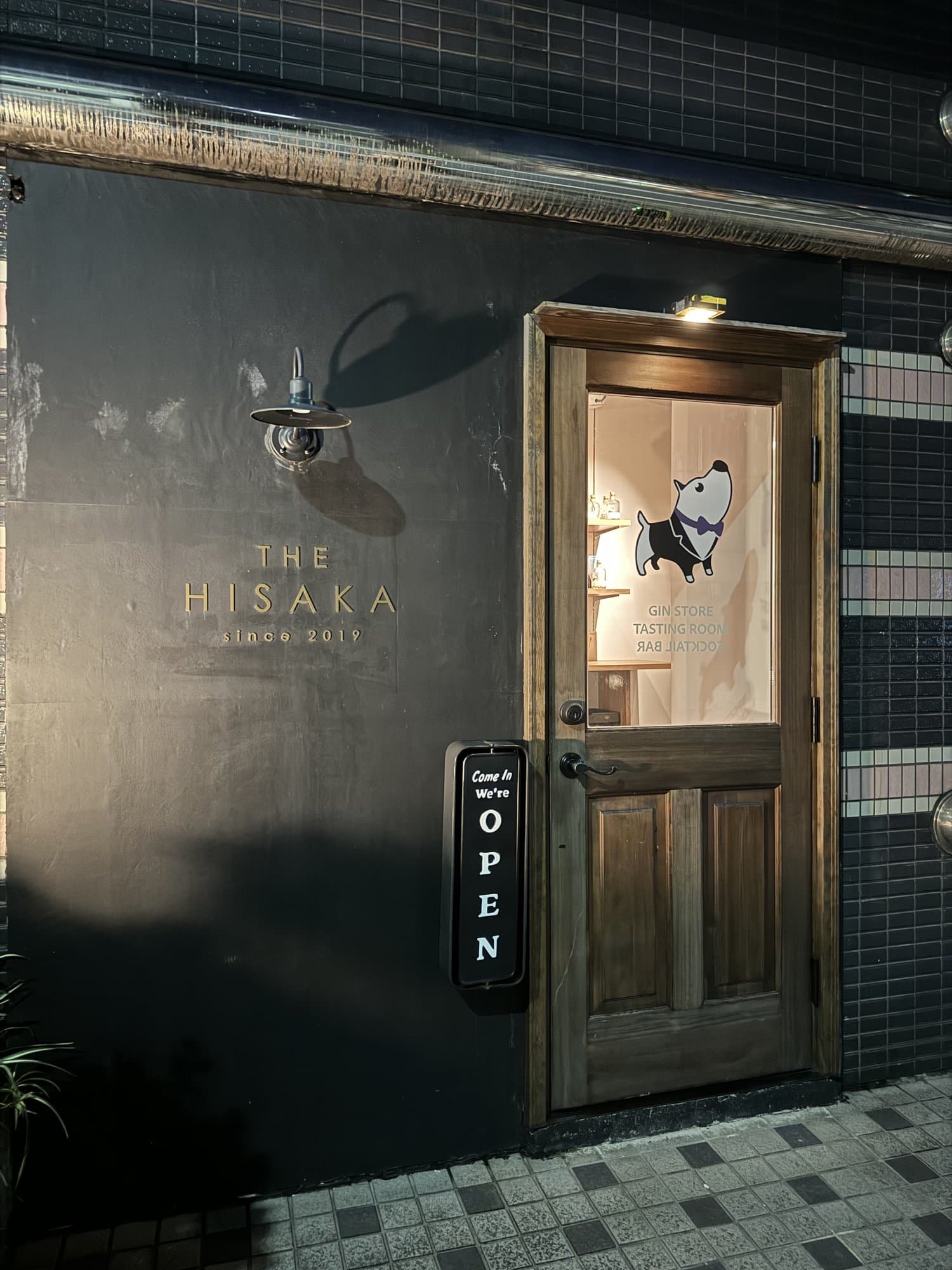 THE HISAKAの外観。黒い壁の店名と、灯りのともる木の扉